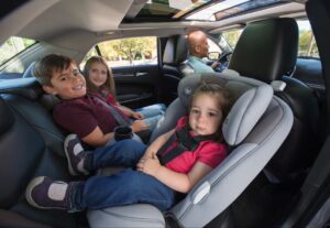 A rear-facing car seat lightly touching the seatback of the front seat.
